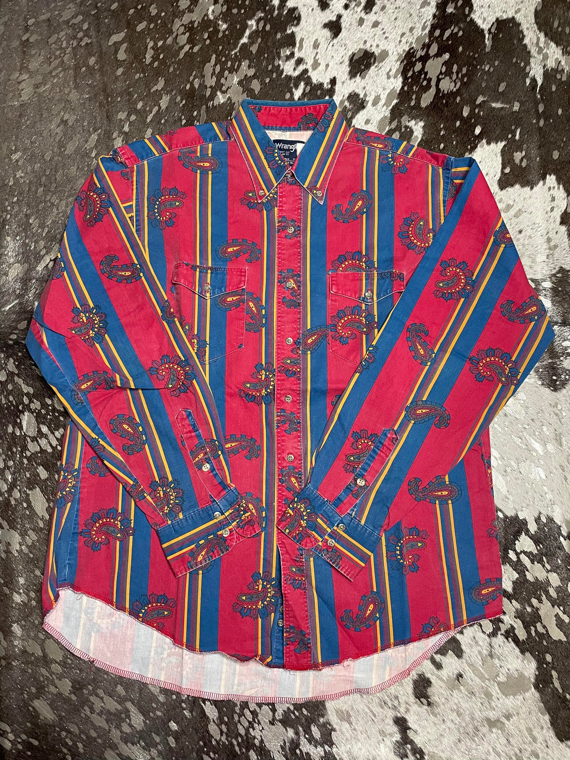 Red base button up with blue and yellow stripes and scattered paisley emblem.